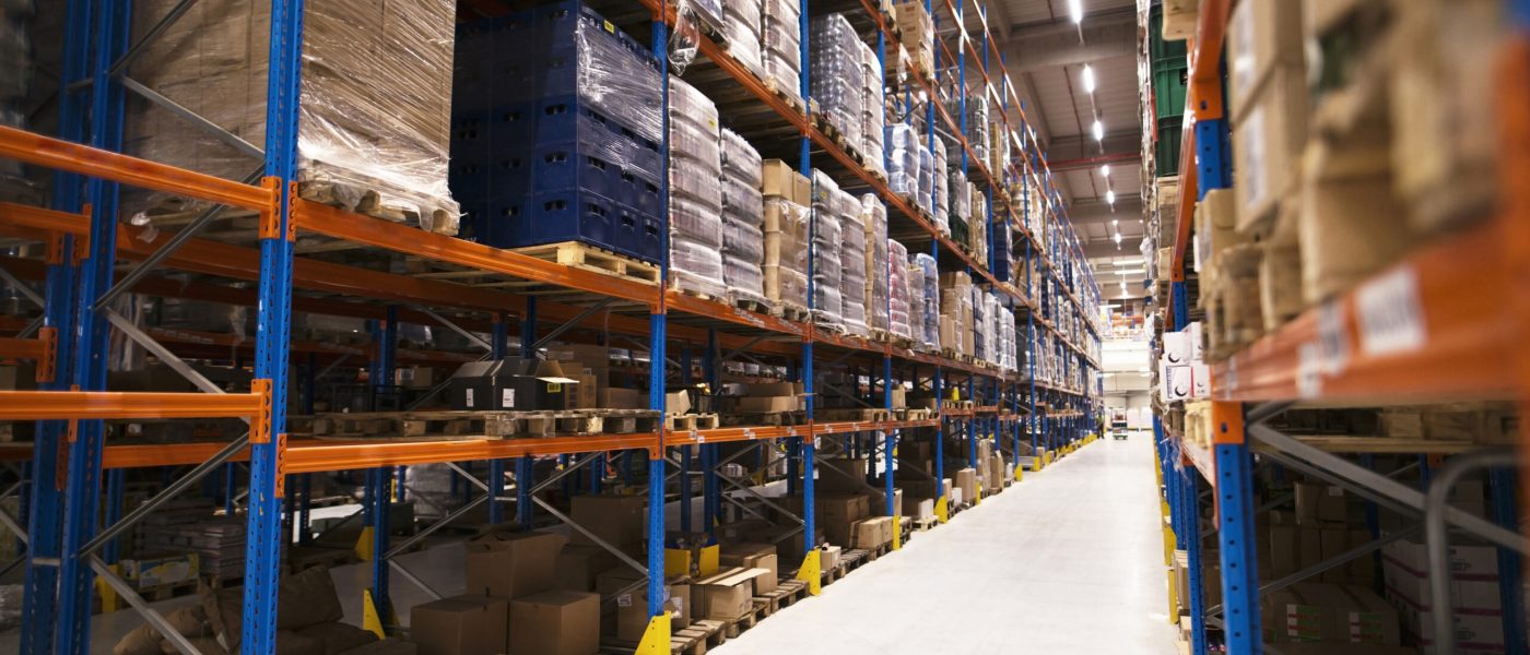 Interior of large distribution warehouse with shelves stacked with palettes and goods ready for the market.